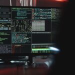 Close-up of a computer monitor displaying cyber security data and code, indicative of system hacking or programming.